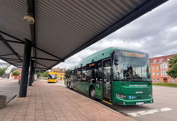 Grön buss står på stationen.