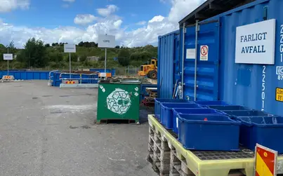 Blå containrar för avfall på en ramp där det går att köra upp med bil.